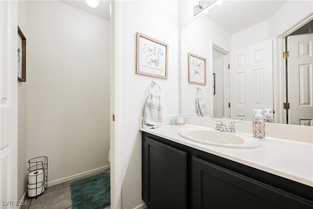 bathroom with toilet, vanity, and tile patterned floors