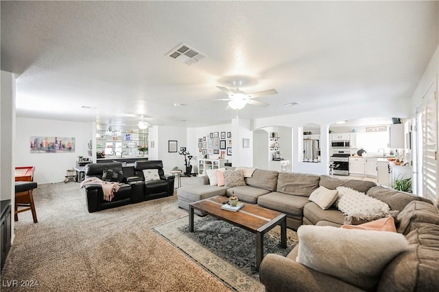 living room featuring ceiling fan, sink, and carpet flooring