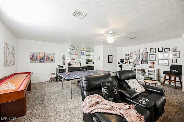 living room featuring ceiling fan, carpet, a textured ceiling, and bar