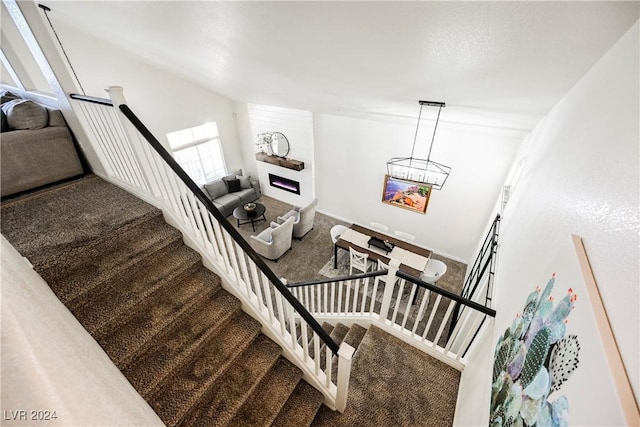 stairway with an inviting chandelier and carpet flooring