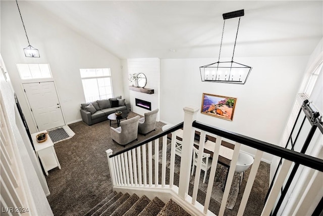 stairs featuring a fireplace, high vaulted ceiling, and carpet floors