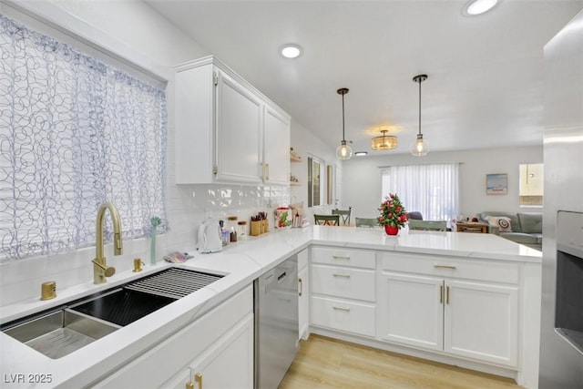 kitchen featuring backsplash, kitchen peninsula, stainless steel dishwasher, and decorative light fixtures