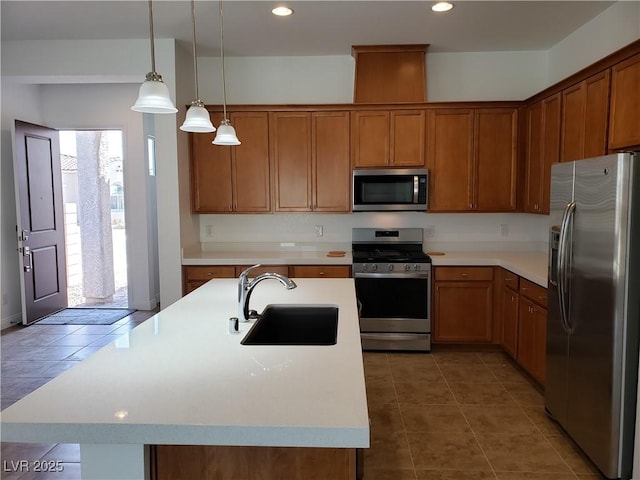 kitchen featuring decorative light fixtures, sink, stainless steel appliances, and a kitchen island with sink