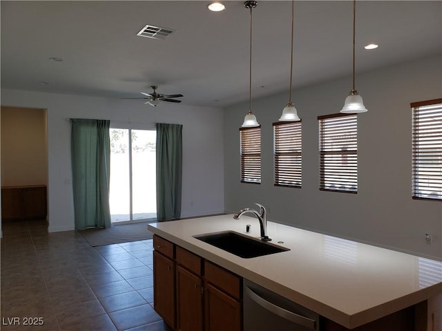 kitchen with dishwasher, a kitchen island with sink, tile patterned floors, hanging light fixtures, and sink