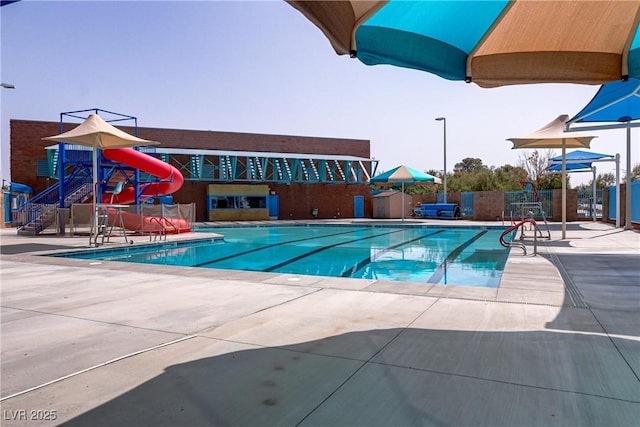 view of pool with a water slide and a patio