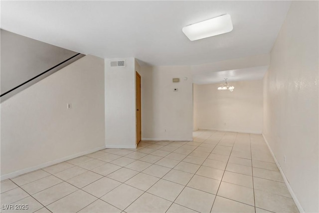 tiled spare room featuring a chandelier