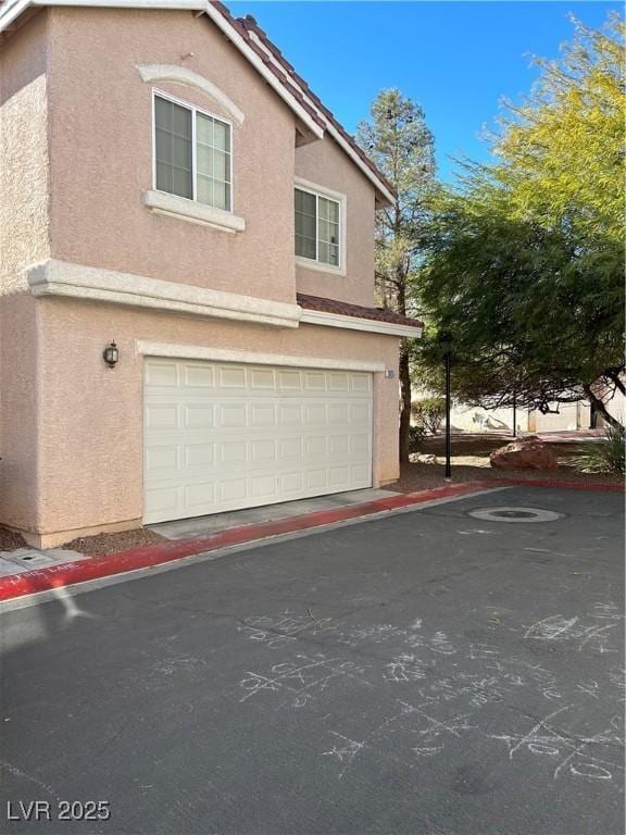 3025 Sunrise Bay Ave, North Las Vegas, NV 89031 - view of side of property with stucco siding, an attached garage, a tile roof, and driveway