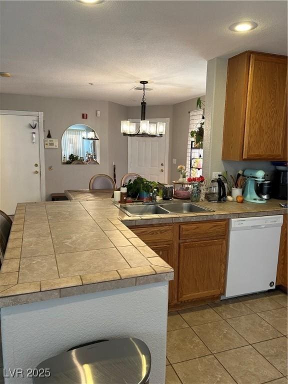 kitchen featuring pendant lighting, an inviting chandelier, white dishwasher, sink, and kitchen peninsula