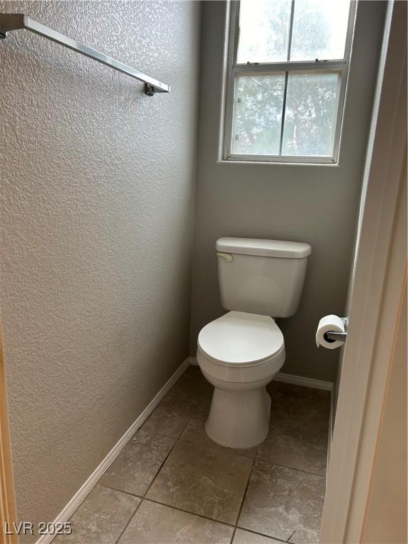 3025 Sunrise Bay Ave, North Las Vegas, NV 89031 - bathroom with toilet, baseboards, tile patterned flooring, and a textured wall