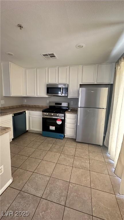 3025 Sunrise Bay Ave, North Las Vegas, NV 89031 - kitchen featuring stainless steel appliances, white cabinetry, light tile patterned floors, and a textured ceiling