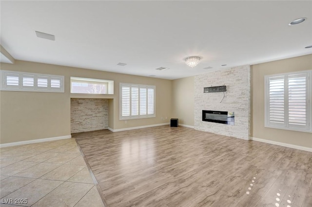 unfurnished living room featuring a stone fireplace and light wood-type flooring