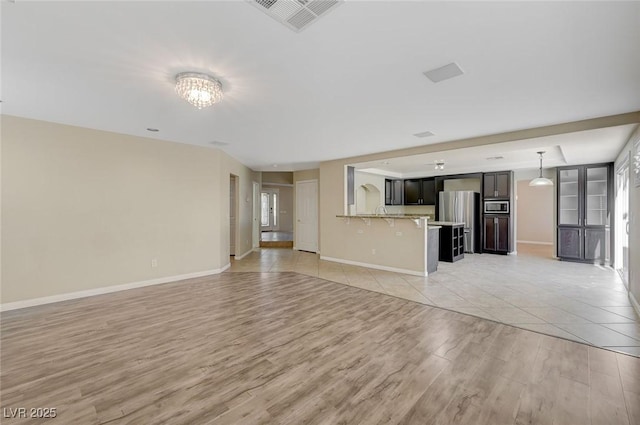 unfurnished living room featuring a chandelier and light hardwood / wood-style flooring