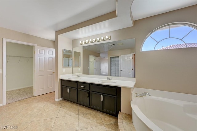 bathroom with a bathing tub, vanity, and tile patterned flooring