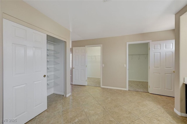 unfurnished bedroom featuring light tile patterned flooring, a walk in closet, and a closet