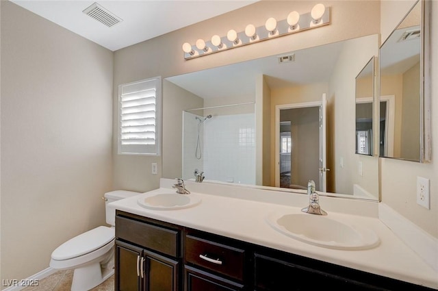 bathroom with tile patterned flooring, vanity, toilet, and walk in shower