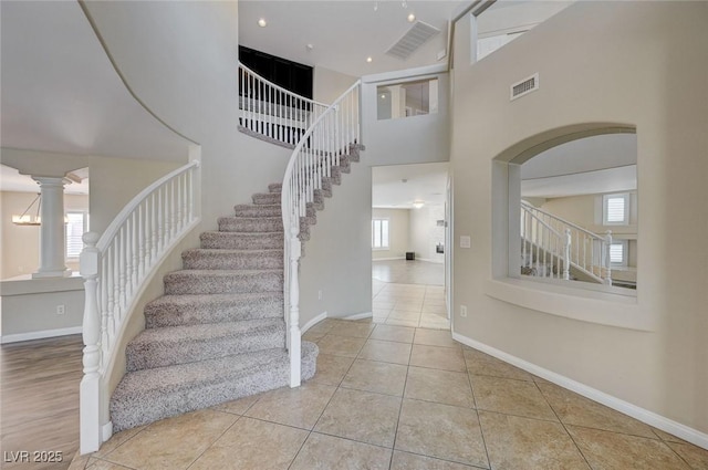 tiled entryway featuring ornate columns, plenty of natural light, and a towering ceiling