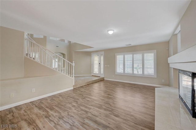 unfurnished living room featuring a tiled fireplace and light wood-type flooring