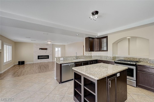 kitchen with dark brown cabinetry, a kitchen island, light tile patterned floors, and appliances with stainless steel finishes