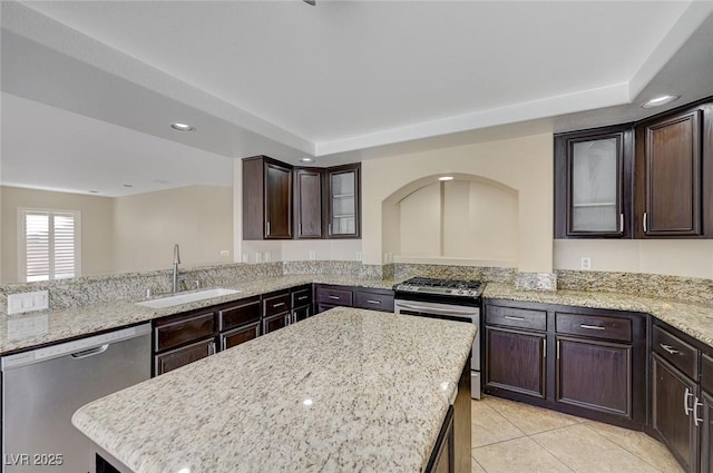 kitchen with light stone counters, a kitchen island, sink, and stainless steel appliances