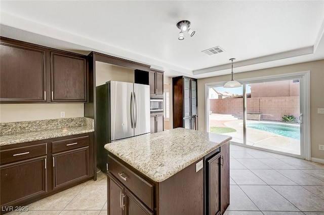 kitchen featuring dark brown cabinets, light stone countertops, stainless steel appliances, and hanging light fixtures