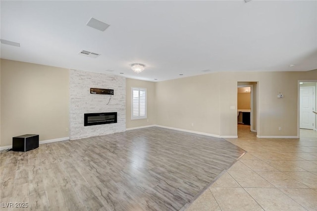 unfurnished living room featuring a stone fireplace and light tile patterned floors