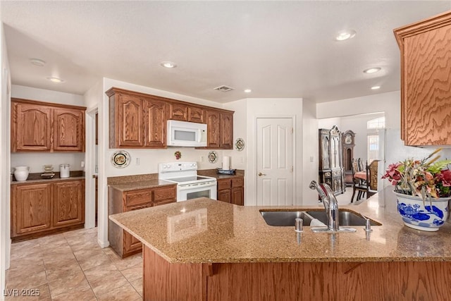 kitchen with kitchen peninsula, light stone countertops, sink, and white appliances