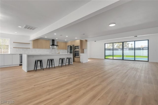 unfurnished living room with beverage cooler and light wood-type flooring