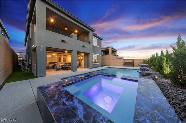 pool at dusk featuring outdoor lounge area, a patio area, and an in ground hot tub