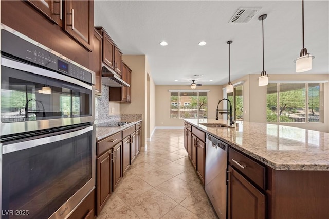 kitchen featuring sink, hanging light fixtures, an island with sink, tasteful backsplash, and stainless steel appliances