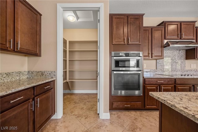 kitchen featuring double oven, black electric cooktop, light stone counters, and tasteful backsplash