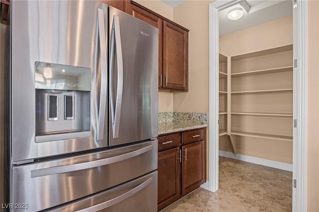 kitchen with light stone counters and stainless steel refrigerator with ice dispenser