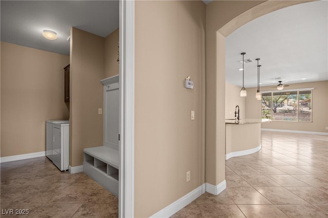 corridor with light tile patterned floors, separate washer and dryer, and sink