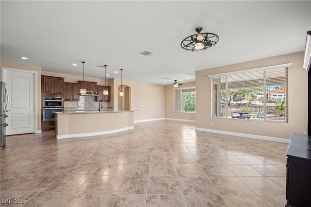 unfurnished living room featuring light tile patterned floors, ceiling fan, and sink