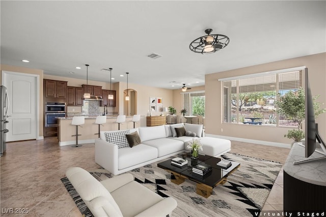 tiled living room with ceiling fan and sink