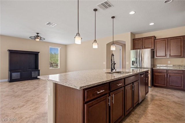 kitchen with sink, hanging light fixtures, ceiling fan, an island with sink, and dark brown cabinetry