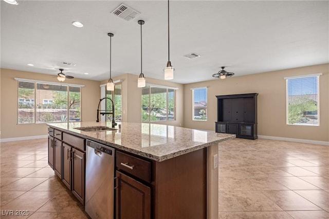 kitchen with light stone countertops, ceiling fan, sink, dishwasher, and an island with sink