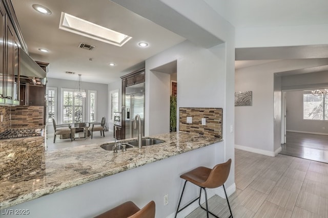 kitchen with a skylight, sink, stainless steel appliances, tasteful backsplash, and kitchen peninsula