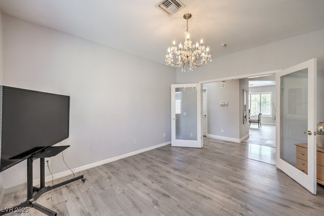 interior space with french doors, light hardwood / wood-style floors, and an inviting chandelier