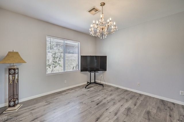 unfurnished living room with a chandelier and light hardwood / wood-style floors