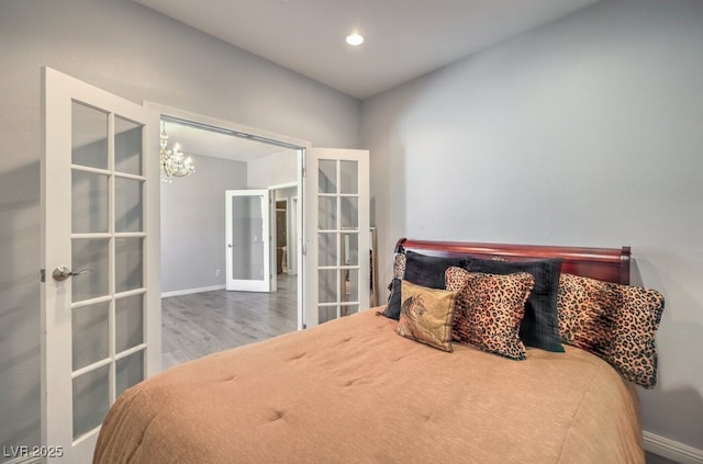 bedroom featuring hardwood / wood-style flooring, an inviting chandelier, and french doors