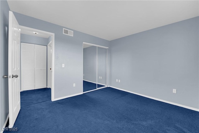 unfurnished bedroom with dark carpet and a closet