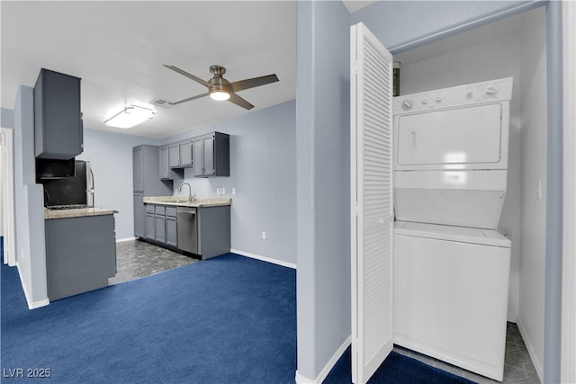 kitchen featuring ceiling fan, stacked washing maching and dryer, stainless steel dishwasher, refrigerator, and gray cabinets