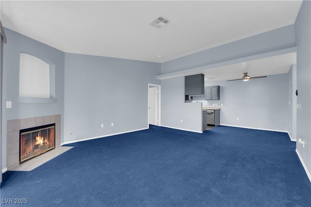 unfurnished living room featuring a fireplace, dark carpet, and ceiling fan