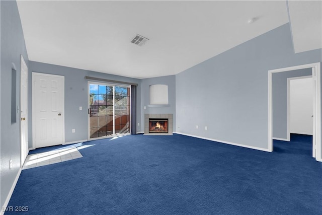 unfurnished living room featuring a tiled fireplace, vaulted ceiling, and dark colored carpet