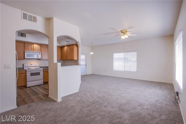 kitchen with hanging light fixtures, ceiling fan, dark carpet, and white appliances