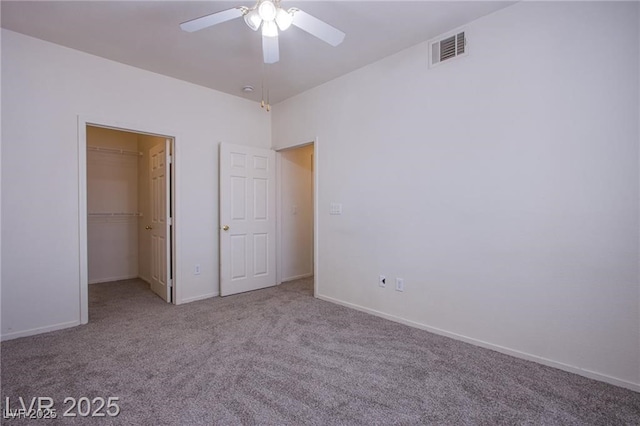 unfurnished bedroom with ceiling fan, a walk in closet, and carpet floors