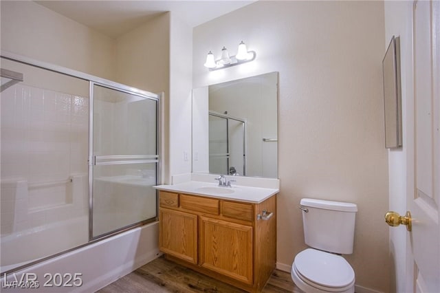 full bathroom with vanity, hardwood / wood-style flooring, combined bath / shower with glass door, and toilet