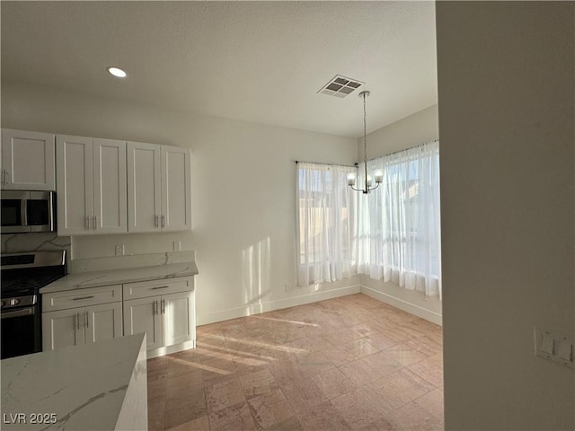 kitchen with pendant lighting, stainless steel appliances, white cabinetry, and light stone counters