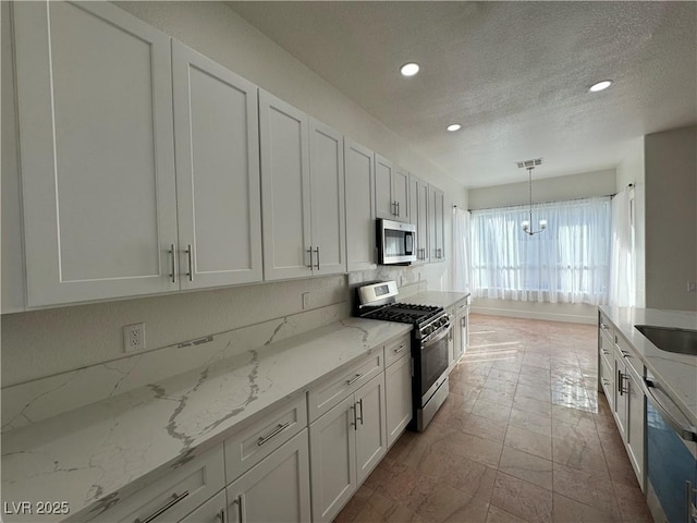 kitchen featuring white cabinetry, stainless steel appliances, and decorative light fixtures