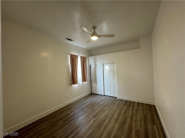 unfurnished bedroom with ceiling fan, dark hardwood / wood-style floors, and a closet